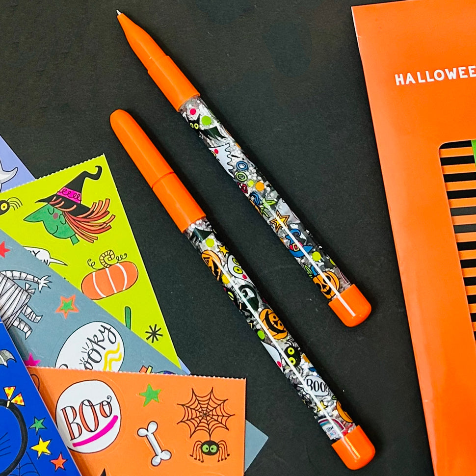 Decorative pen with Halloween-themed design on a black surface with Halloween-themed stickers.